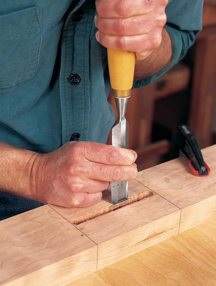 chisels away at a wooden block