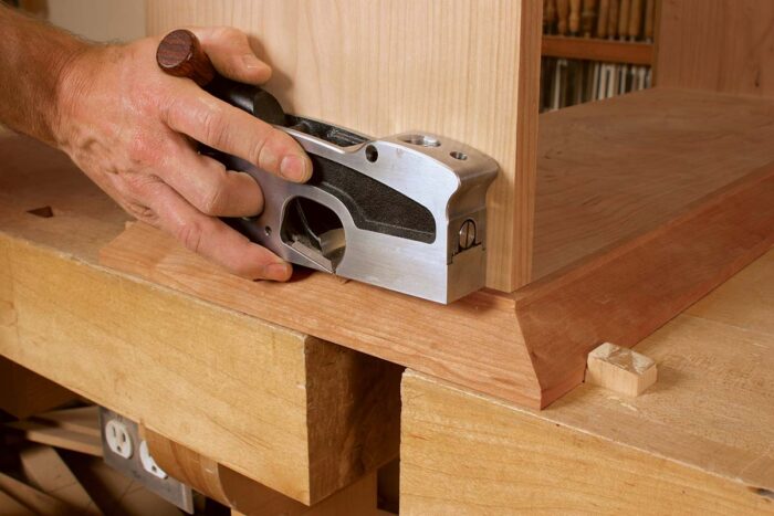 The top edges of the front and side base moldings were slightly misaligned. Gochnour uses a shoulder plane to get the parts flush.