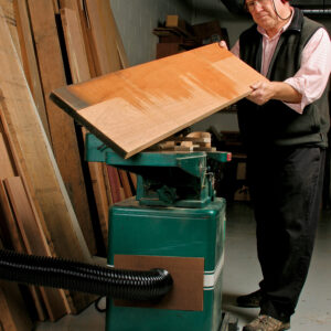 man looking at a warped board that needs additional passes on the jointer