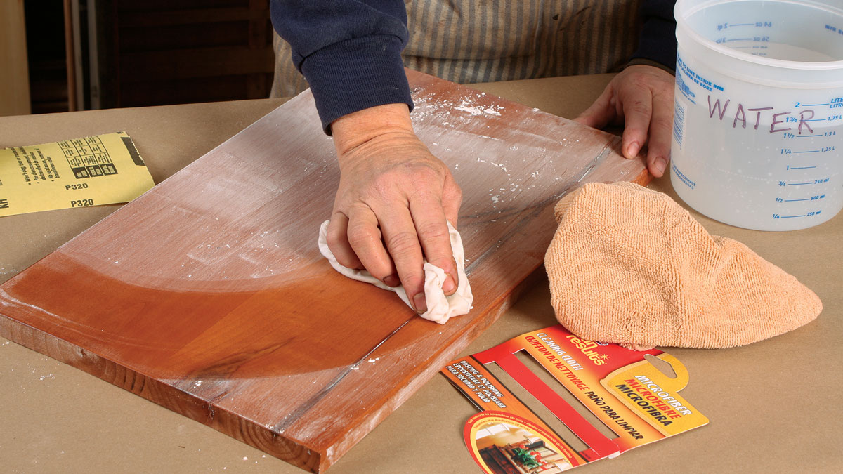 No tack cloth, please Use a damp cotton or microfiber cloth to wipe away sanding dust. A sticky tack cloth can leave residue that will repel water-based finishes.