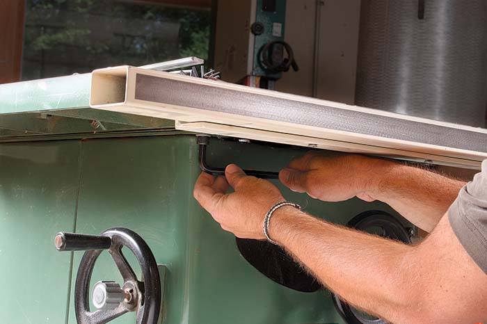Loosen three of the four bolts that attach the table to the saw cabinet