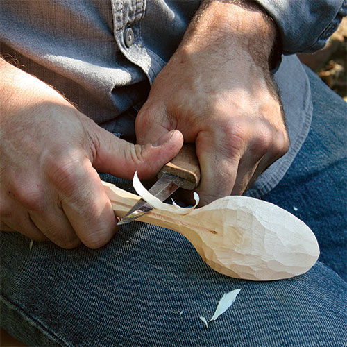 carving a wooden spoon with a knife