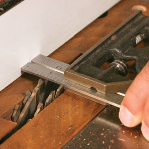 The fence controls the tenon’s length. Use a combination square to set the fence position.