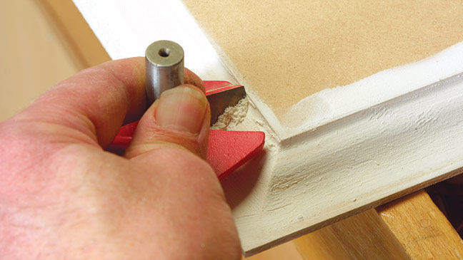 Scraping away excess compound from an MDF face with a router-bit.