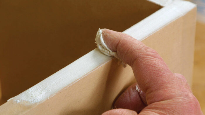 Applying drywall compound putty to MDF with a finger instead of a putty knife.