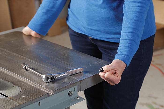 After loosening three of the bolts that attach the top to the cabinet, use the tight bolt as a pivot point to bring the miter slot into parallel with the blade. 