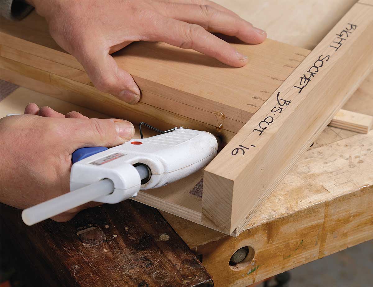 Set a stop. After laying out the baseline on a piece of scrap, cut to it and leave the jig in place. Clamp a rounded stop against the jig’s leading edge, touching the kerf. Use a C-clamp, as the saw’s vibration can work an F-style clamp loose.
