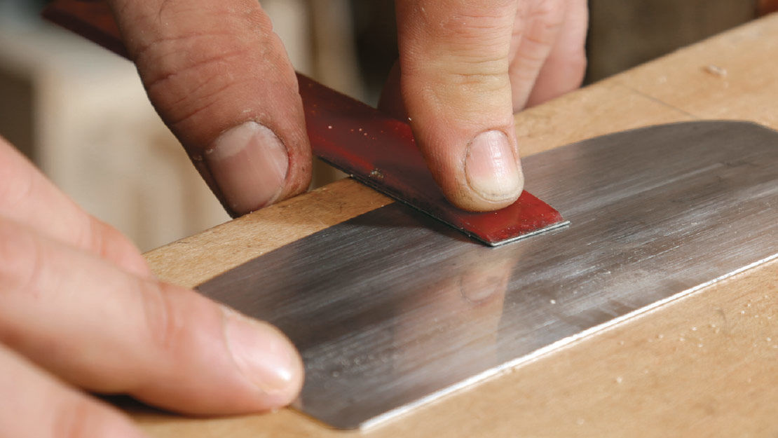 Use the fine diamond hone to flatten the face of the scraper, being careful never to tilt the hone. Then hone the edge again.