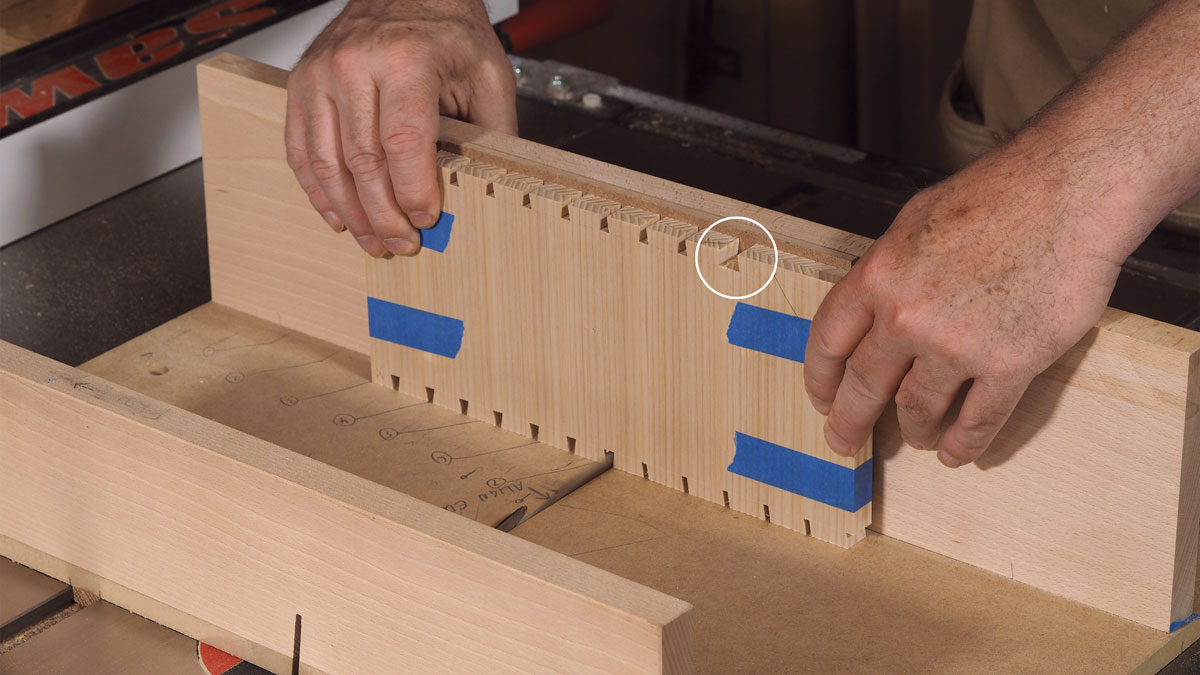  Cut tails in both sides at once. The author uses a tablesaw blade ground for dovetails, but whether you cut them by hand or machine, taping the sides together will make faster work of the many dovetails. Create an extrawide pin socket (circled) at the front of the top edge to make scribing for the case top easier later.