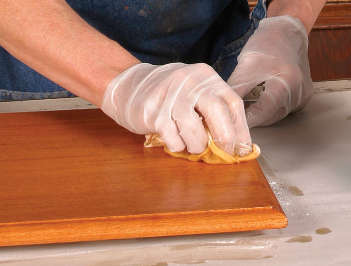 Man rubbing in the pumice linseed oil combination on a board in order to pack the pores.