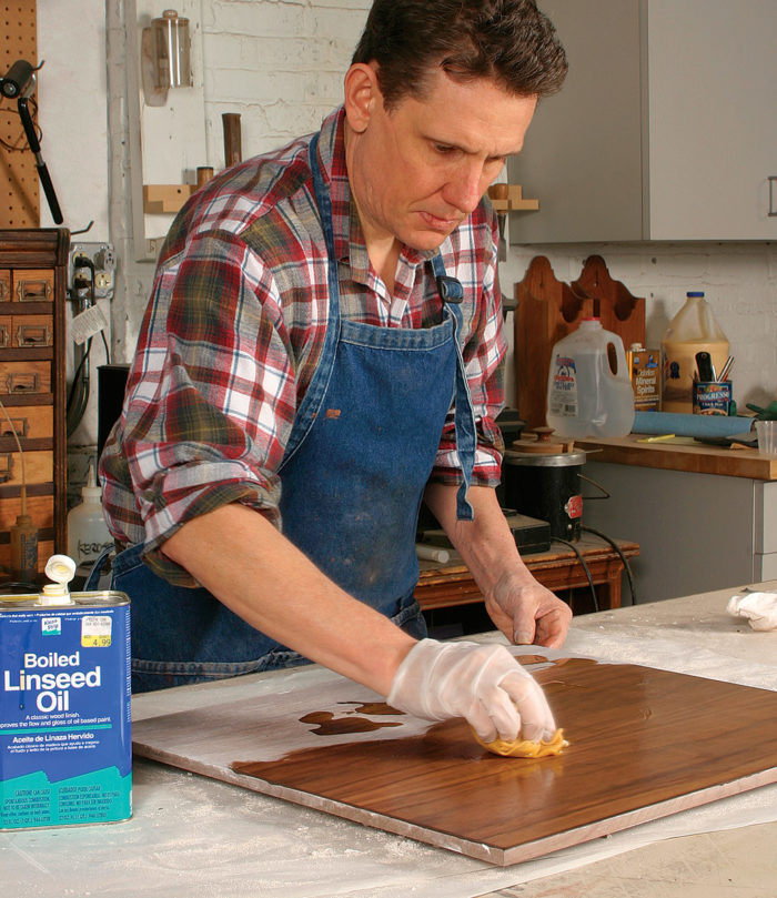 Man applying boiled linseed oil to a board after packing with plaster of paris.