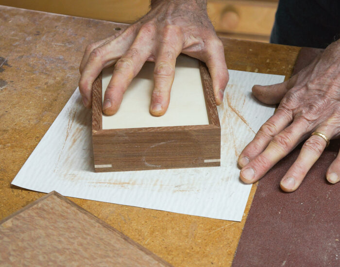 Using sandpaper on a workbench to sand box edges