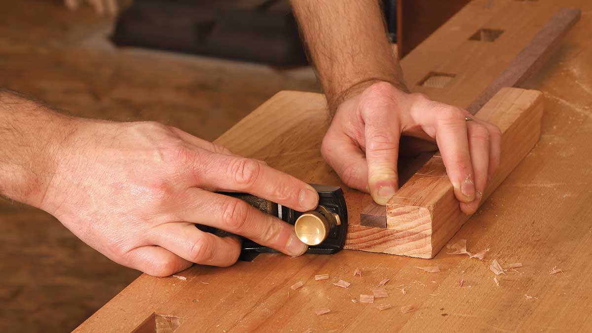 Fairing a miter. Rather than using a clamp to hold a mitered workpiece, Korsak holds it on edge with one hand and planes with the other. He does the same to plane end grain on most square-cut boards, steadying them on one edge with one hand while planing in a downstroke with the other.