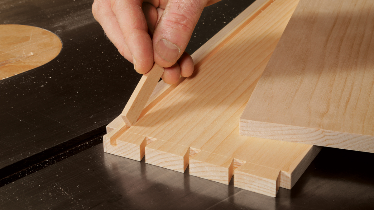 A dovetailed drawer side with a groove. Tom McLaughlin uses a test piece of wood to check the size of the groove to make sure it will fit the drawer bottom.