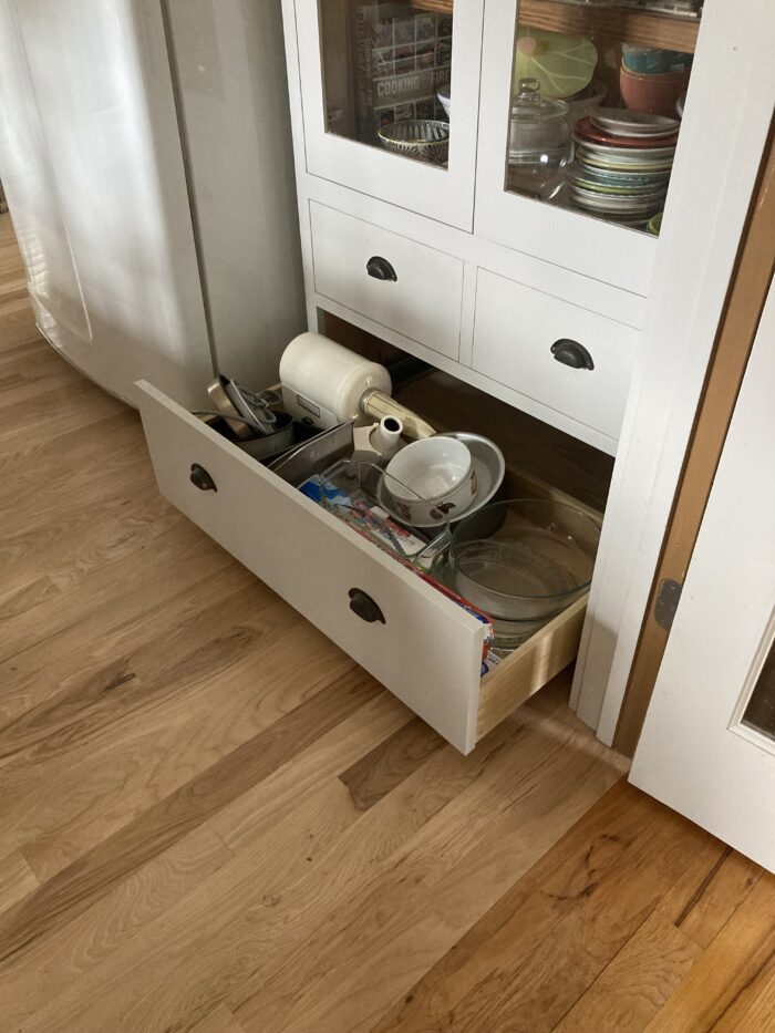 A wide, white kitchen drawer with low sides, fully extended.