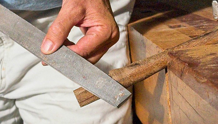 Karen McBride uses a file to round the tenon corners of the hammer handle.