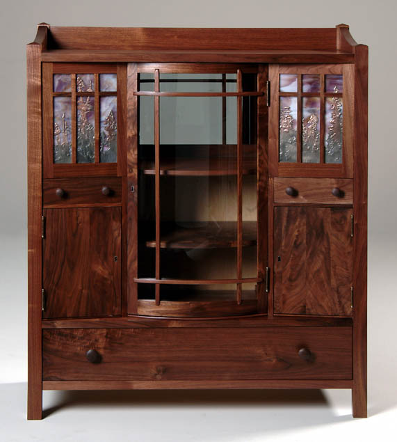 A walnut china cabinet with curved glazed door.