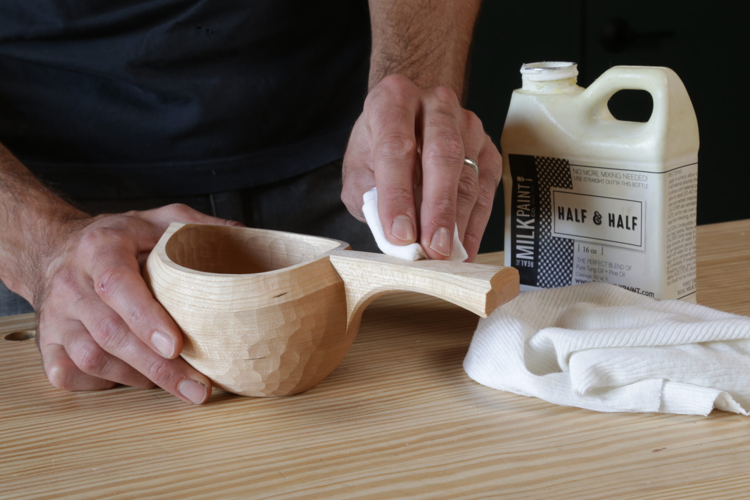 applying thin coats of oil to a cup carved from greenwood