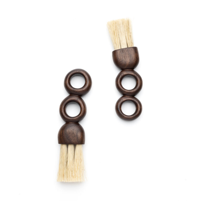 Two brushes with wooden handles carved to look like rings standing on top of one another.