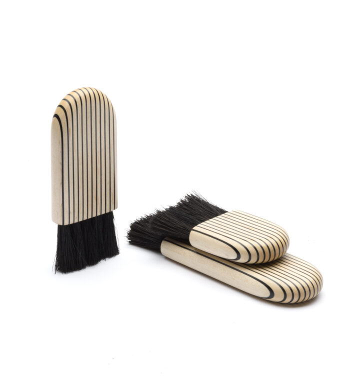 Three brushes made of of alternating white and black wood.