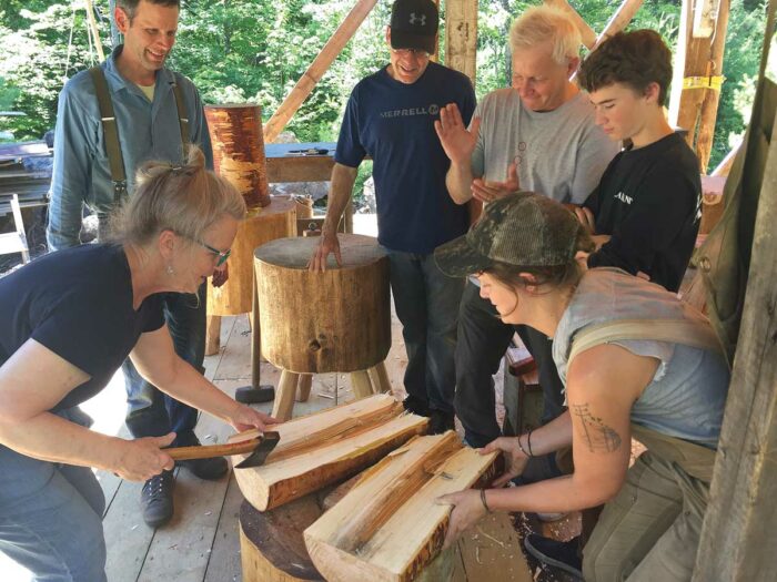 class of people working on wooden logs with an axe