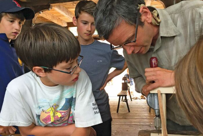 teacher working with children on a woodworking project