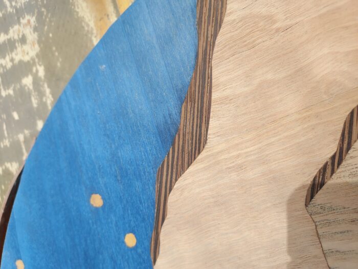 The dark brown wenge in this veneer art is thicker and harder than the dyed blue poplar.