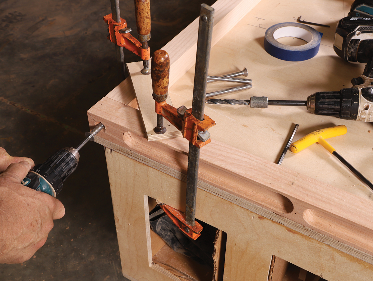 Pre-cut threads. With one pair of legs and long rails clamped on a flat surface, Boggs first drilled clearance and pilot holes and cut a countersink, and then, as shown here, he drove a bolt dry to pre-cut threads in the pilot hole.