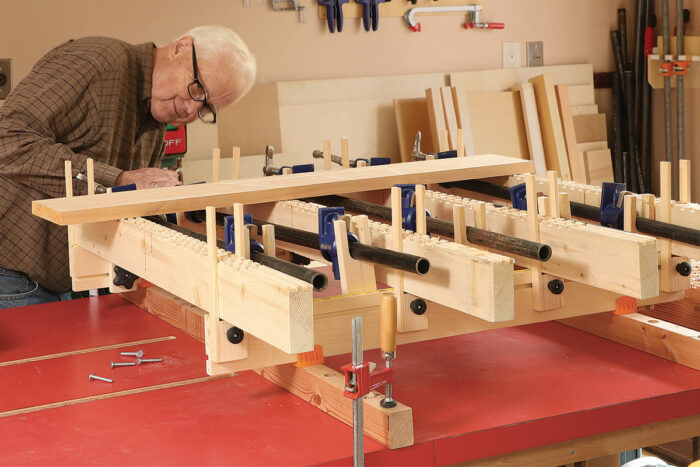 McIvor adjusts the height of the clamp holders so the clamp screws are centered on the thickness of the plank