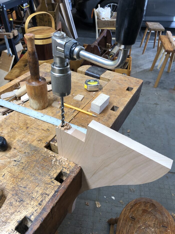 A photo showing the table wing being drilled by hand with a brace and bit.