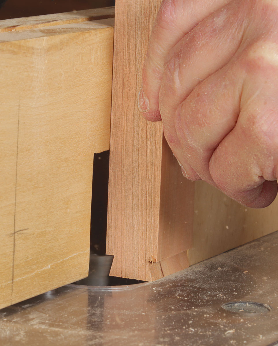 Install the bit in a router table for the tail. By using the same bit, you ensure that the tail and socket have matching angles. Support the workpiece with a square push block. 