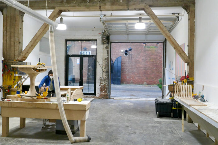 The Ottra Gallery wood shop, including a wide jointer and planer, a panel table saw, shapers, a long bar clamp dock, and a vast CNC machine.