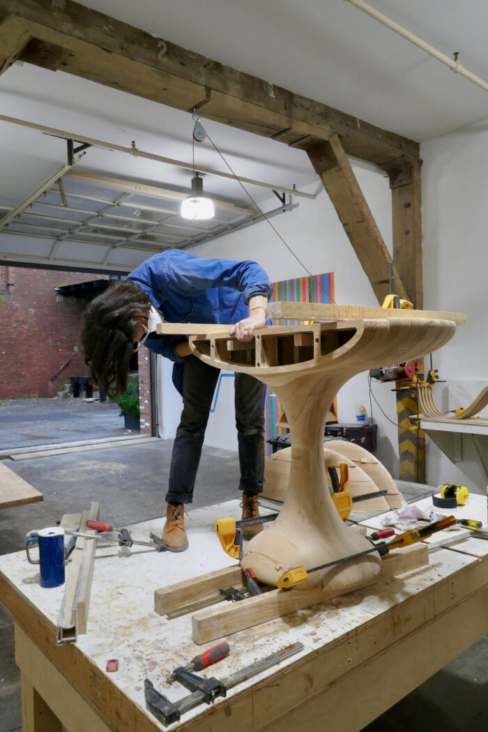 Meghan Arlen glues up the segments of a round solid oak table.