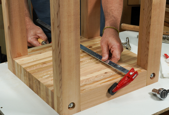 With the nuts tightened on either side, a clamp is applied to the middle of the table top. 