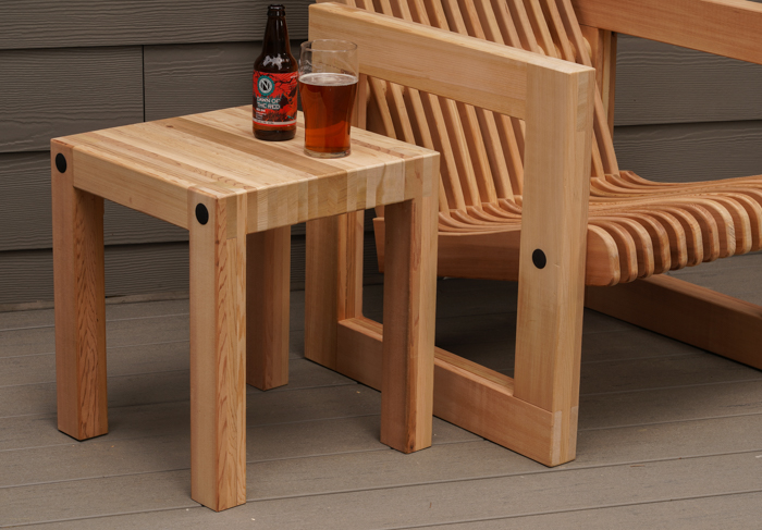 A photo of the completed outdoor table and chair. On top of the table sits a bottle of beer and a glass with beer in it. 