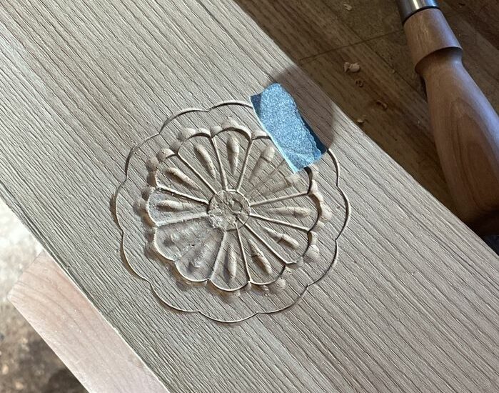 A carving in wood. It's a repeated circular pattern in the shape of a flower. 