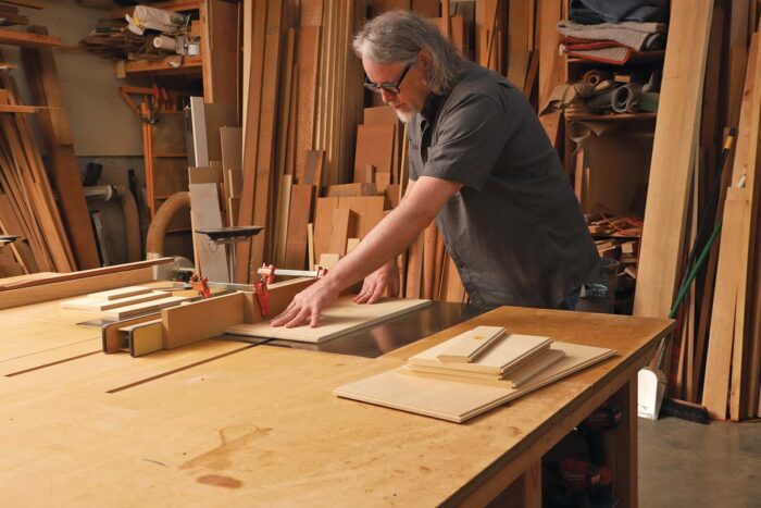 The author pushes a piece of wood over the table saw.