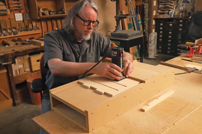 The author uses a router to excavate a groove.