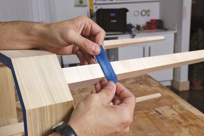 Evan holds the edge of a piece of blue tape against the cavity he created with a knife. the tape flexes as its pushed into the cavity. 