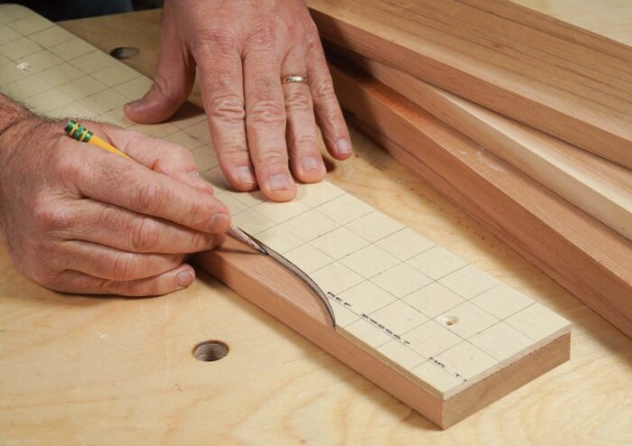 Asa traces the edge of the plywood template onto a piece of cedar. A pencil rides the concave edge of the template. 