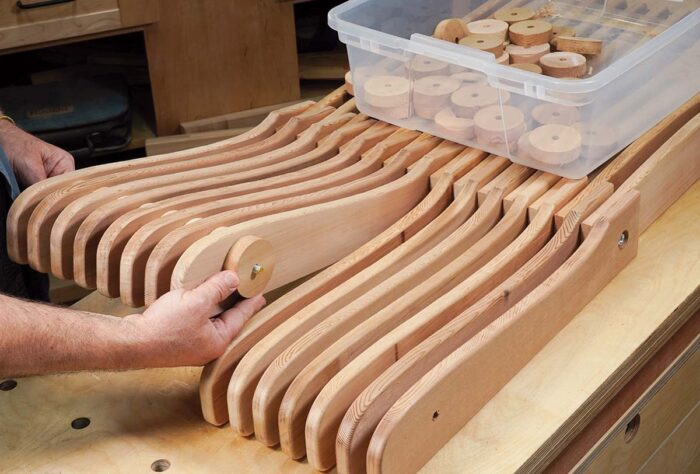Asa arranges a series of slats and wooden disks that make up the chair assembly.