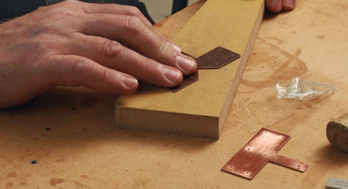 The author is sanding a piece of copper. Next to it is a piece that has already been sanded showing the shine of fresh metal.