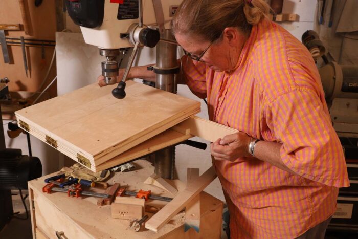 Beth places the spacer on the back of the angled drill press jig. 