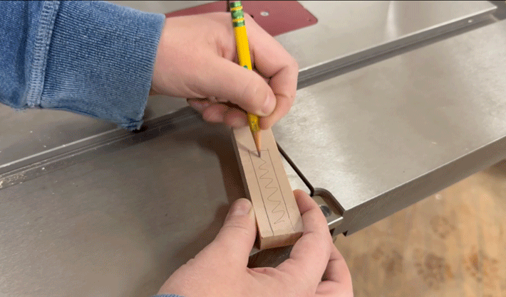 Amanda pencils off a middle section on the small piece of wood she cut at the miter saw. 