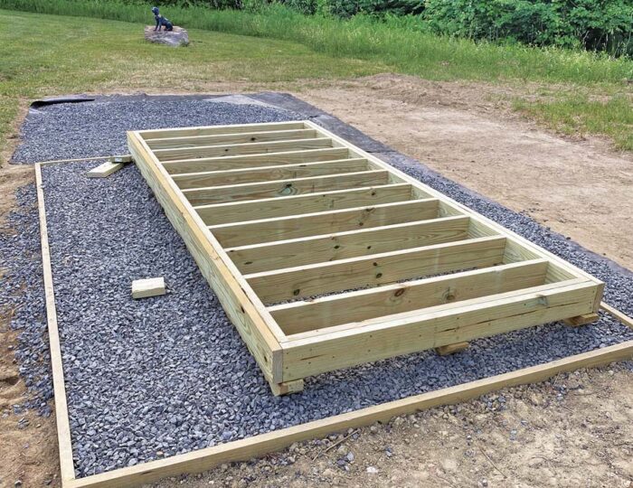 A bed of gravel with the bottom structure of the solar kiln built on top of it.
