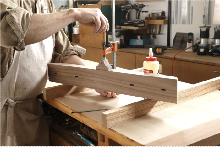 Tom glues the screw block to the top of the leg and uses a clamp to secure it.