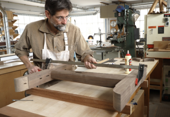 Tom glues the trestle leg together with the sanding block visible. 