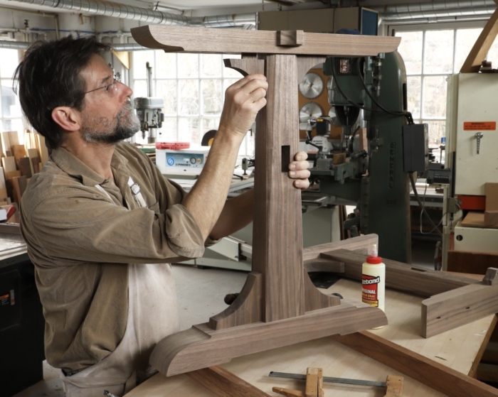 Tom attaches a curved corbel to the top of the leg of a trestle table.