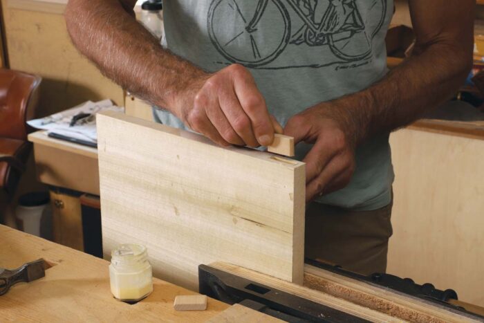Tim inserts a block of maple into the lumber core panel, which will be the plaement of screws once the panel is glued up. 
