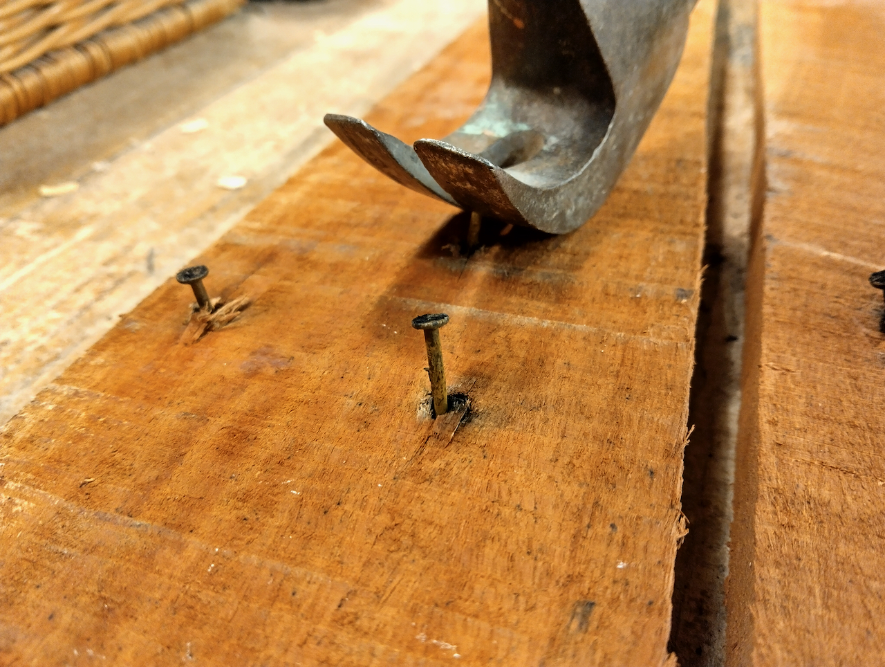 Yoav uses a hammer to pry nails loose from a reclaimed board.